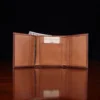 no 1 trifold wallet in brown steerhide on a wooden table with a dark background - front open view with money -business card