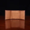 no 1 trifold wallet in brown steerhide on a wooden table with a dark background - front open empty view