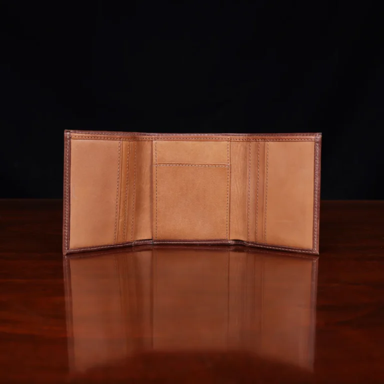 no 1 trifold wallet in brown steerhide on a wooden table with a dark background - front open empty view
