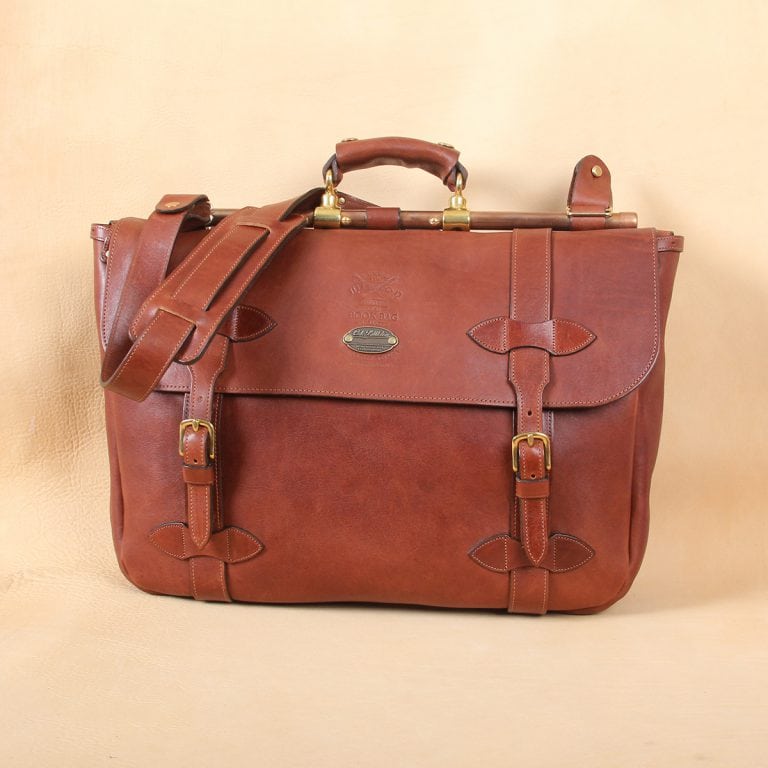 brown leather messenger book bag on table
