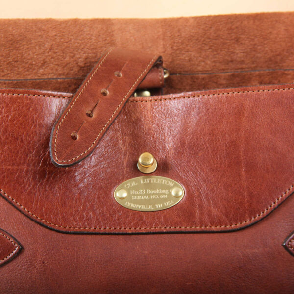 brown leather messenger book bag on table