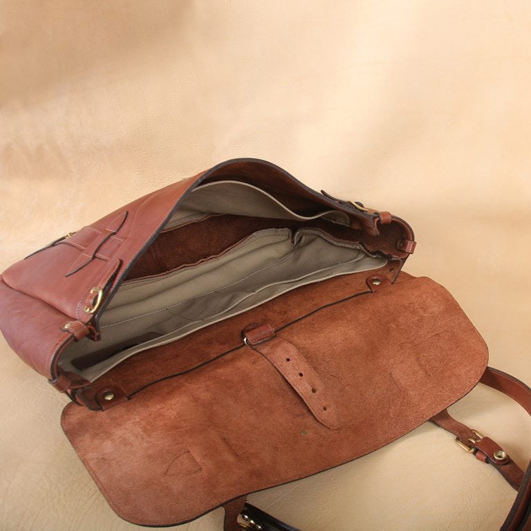 brown leather messenger book bag on table