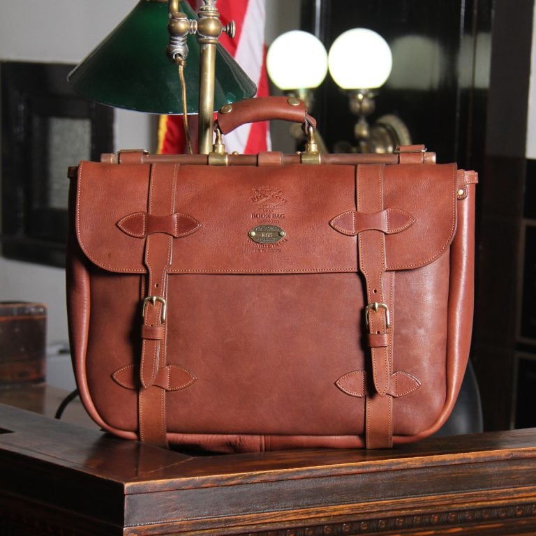 brown leather messenger book bag on table