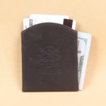 Black leather front pocket wallet back side with Col. Littleton logo embossed in center.
