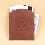 Brown leather front pocket wallet back side with Col. Littleton logo embossed in center.