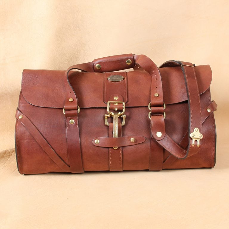 leather travel bag front of bag with brass buckle closed.