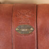 leather travel bag front embossed logo on brown leather with antique brass plate.