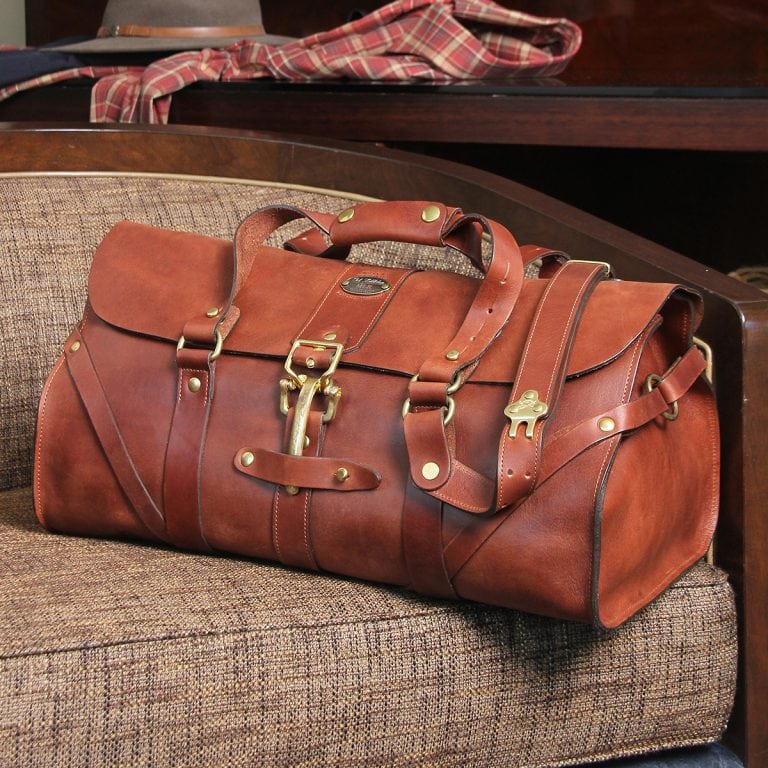 leather travel bag with brass level style buckle on front and vintage brown leather body.