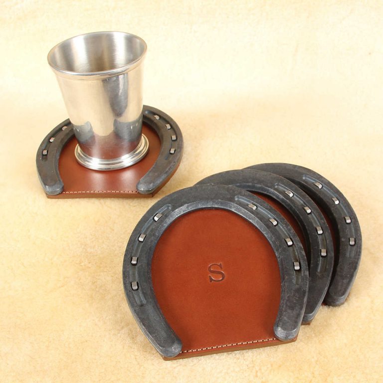 silver cup sitting on top of leather horseshoe coaster