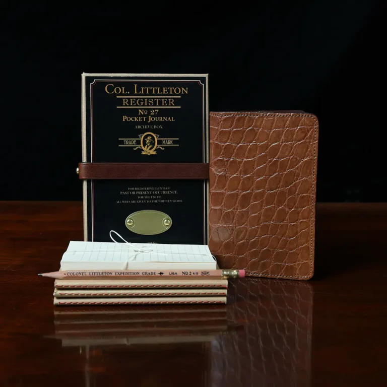 No. 27 Pocket Journal in American Alligator - ID 001 - front view, shown with journal register archive box, 3 journal register notebooks, a stack of cream index notecards, and a Col. Littleton wooden No. 2 pencil - on black background