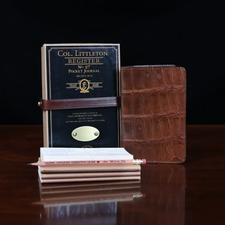 No. 27 Pocket Journal in American Alligator - ID 001 - front view, shown with journal register archive box, 3 journal register notebooks, a stack of cream index notecards, and a Col. Littleton wooden No. 2 pencil - on black background