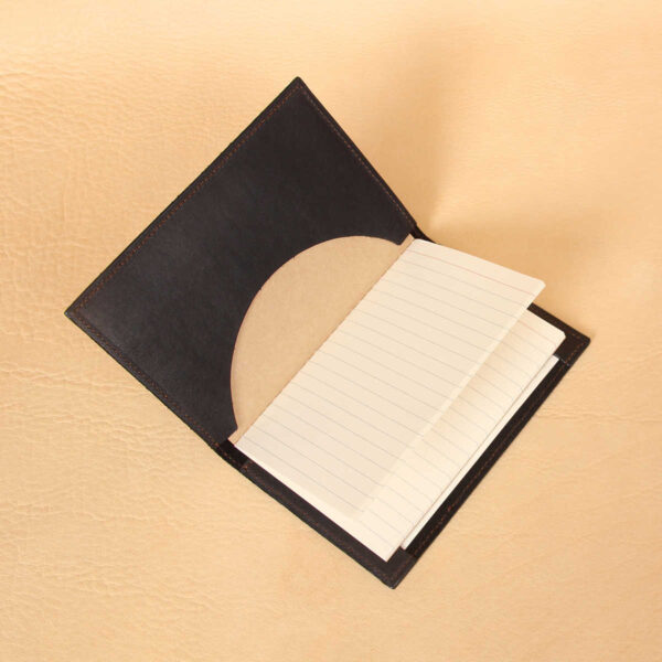 Pocket journal black leather inside registers notebook in pocket open to ruled pages.