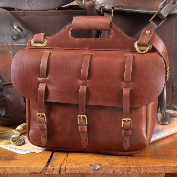 brown leather saddlebag briefcase on wood table