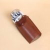 Leather tumbler sleeve for 20 ounce Yeti Rambler cup laying on side with cup coming out of sleeve.