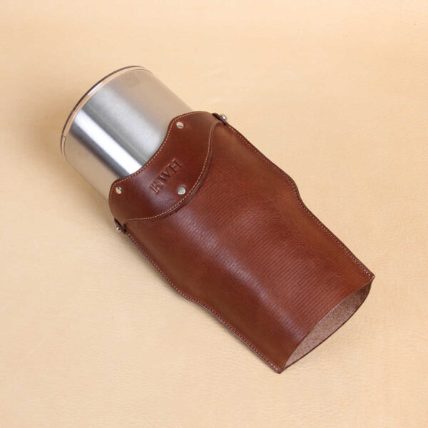 Leather tumbler sleeve for 30 ounce Yeti Rambler cup laying on side with cup coming out.
