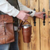 Leather tumbler sleeve for 30 ounce Yeti Rambler cup one finger carrying sleeve by handle heading out the door.