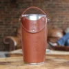 Leather tumbler sleeve for 20 ounce Yeti Rambler cup sitting on coffee table in front of man working.