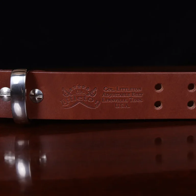 no1 brown leather belt with nickel hardware - logo view - on a wooden table with a black background