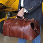 man holding large brown leather travel bag
