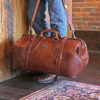 man holding leather travel grip bag