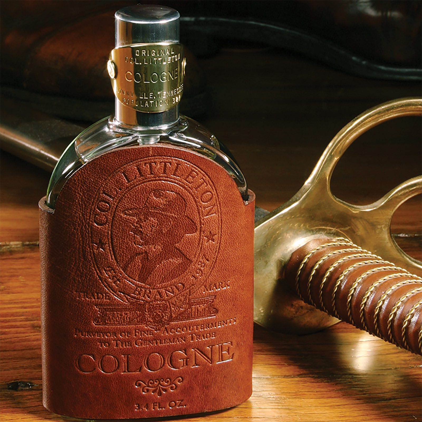A bottle of Colonel Littleton cologne on a wooden table next to the hilt of an antique saber.