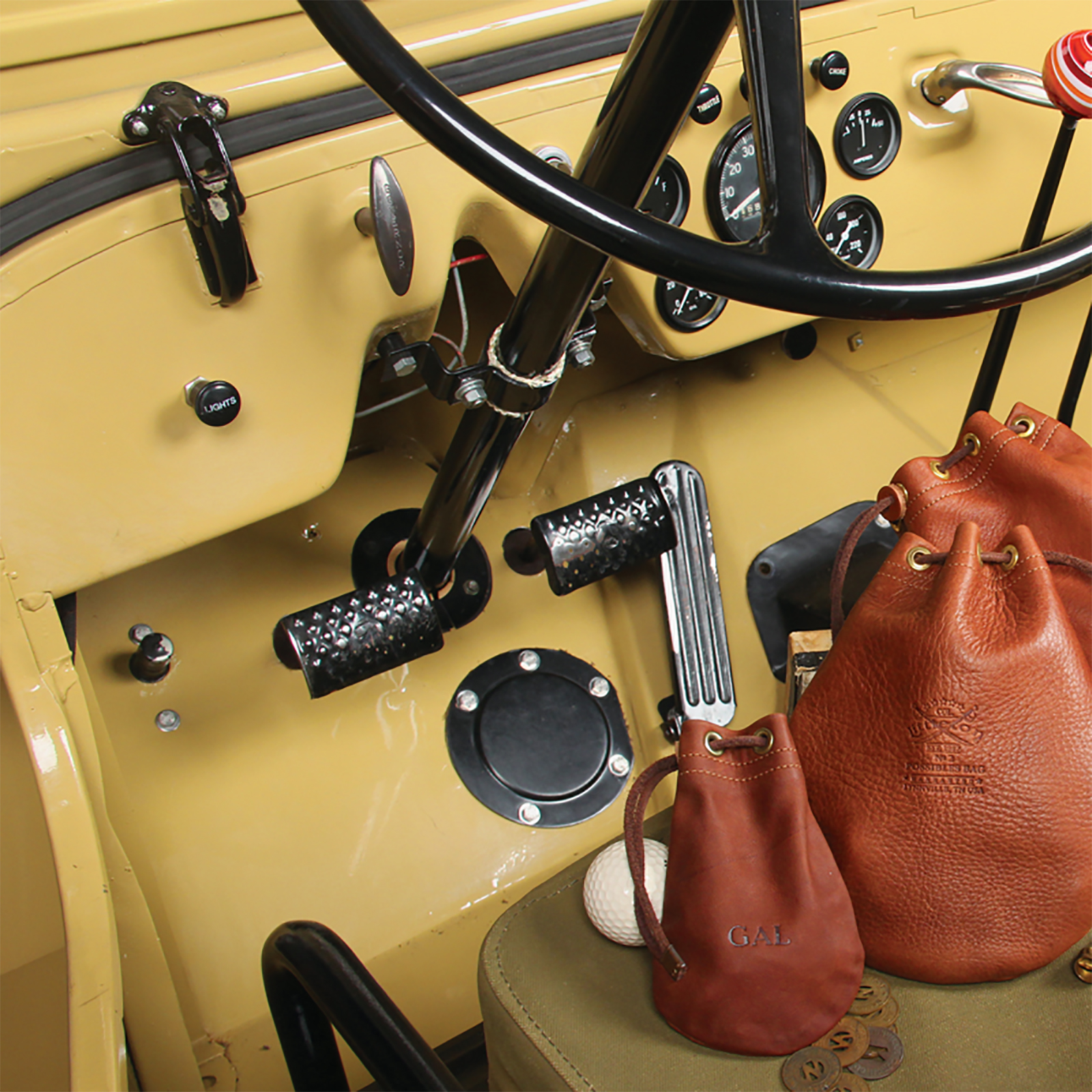Wheel and dash of a 1951 Willy's Jeep with Possibles Bags resting on the seat