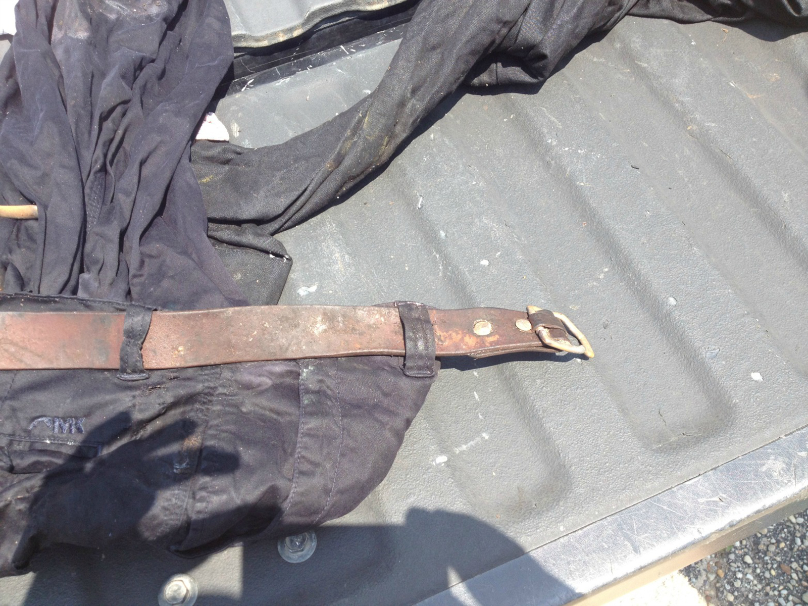Worn and moldy No. 5 Cinch Belt, looped through belt loops on dirty pants, buckle