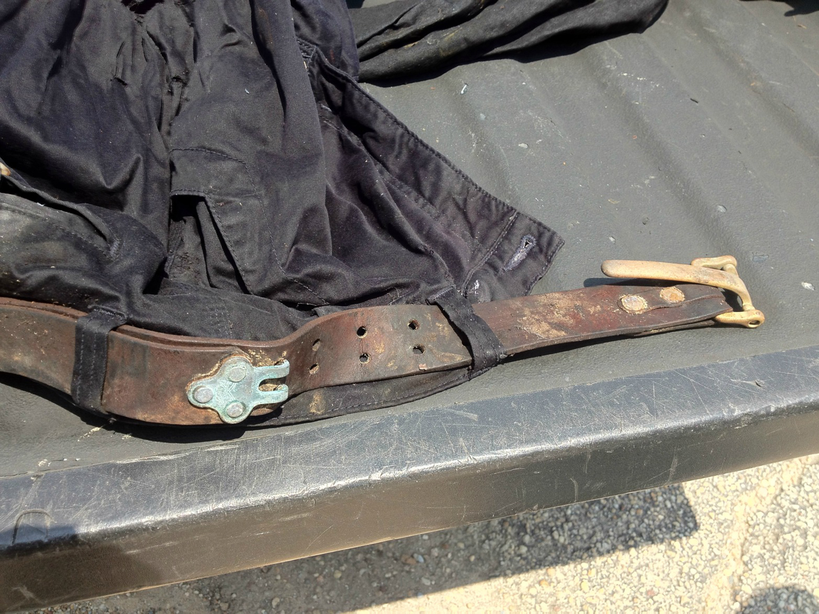 Worn and moldy No. 5 Cinch Belt, looped through belt loops on dirty pants, buckle latch