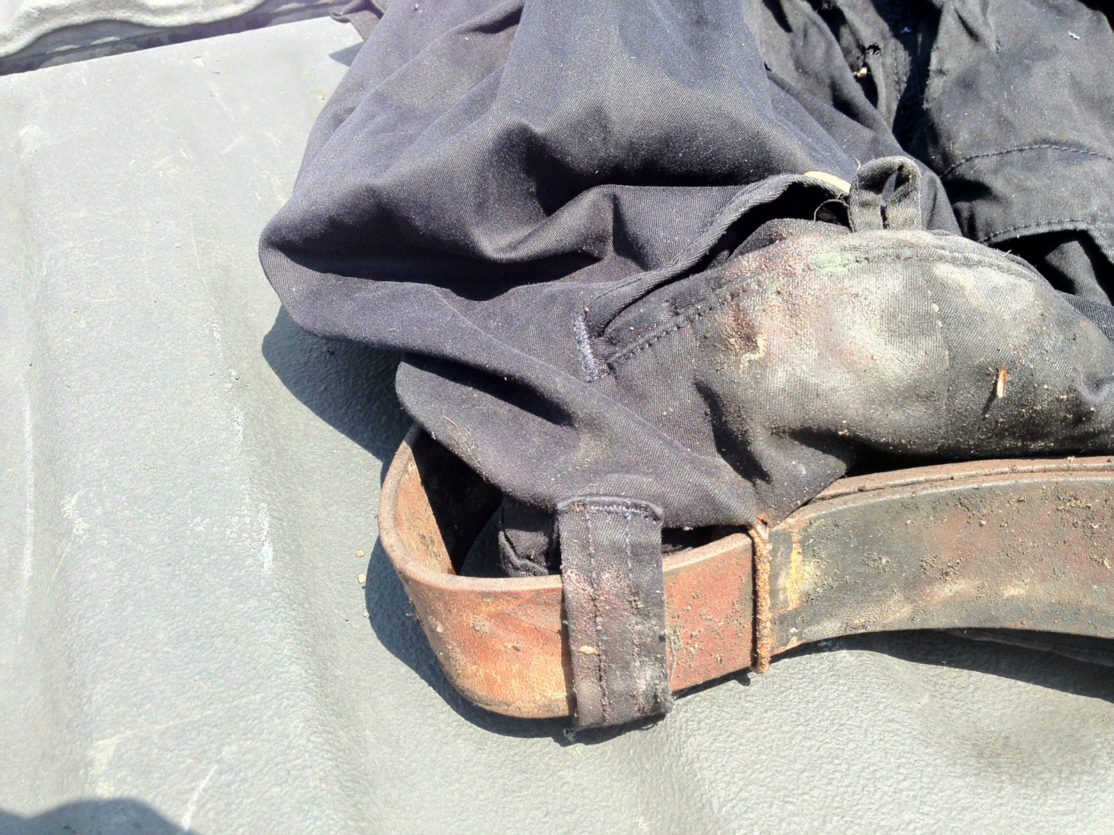 Worn and moldy No. 5 Cinch Belt, looped through belt loops on dirty pants, rusted hardware