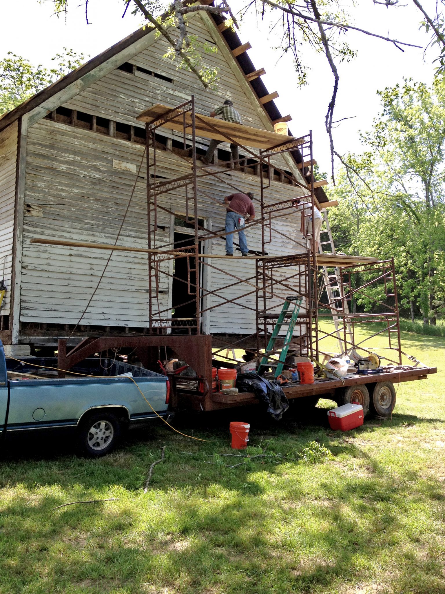 Men on scaffolding painting front of one-room schoolhouse on Foxfire Farm in Lynnville, TN