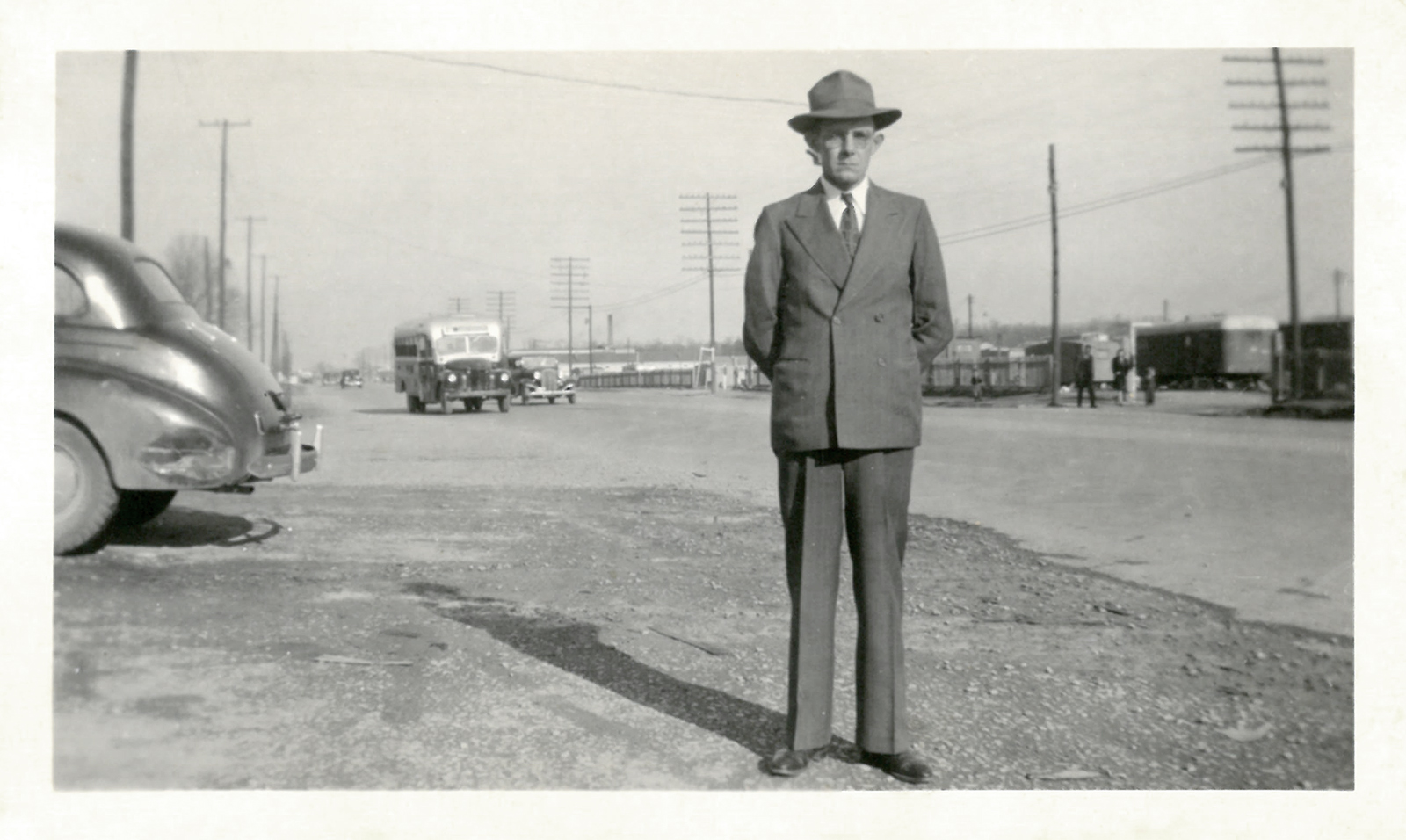 Black and white photo of Colonel's dad standing in a suit and hat at Oak Ridge.