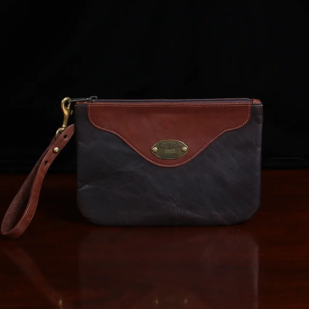 front view brown leather wristlet clutch on black background and wood table