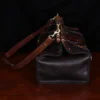 Side view of Dark brown buffalo leather No. 3 grip travel bag sitting on table