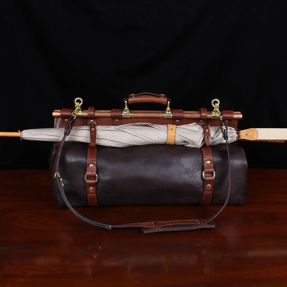 Dark brown buffalo leather No. 3 grip travel bag with an umbrella attached using straps straps