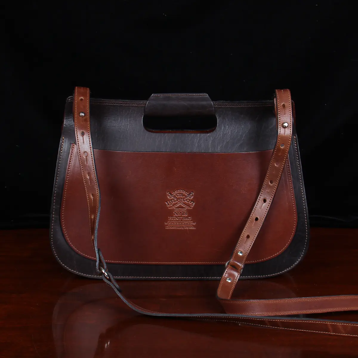 no 18 leather huntbag in tobacco buffalo - back view - on a wood table with dark background
