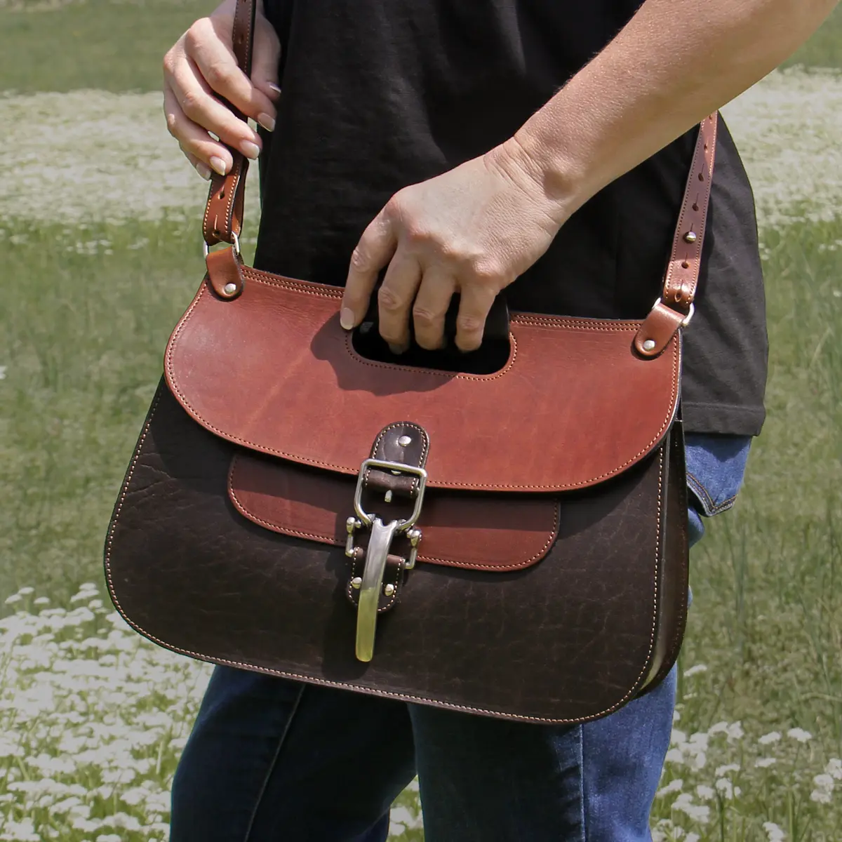 No. 18 Hunt bag in Tobacco Brown American Buffalo with Vintage Brown Steerhide Trim - Woman wearing the bag crossbody with her hand resting on the top handle