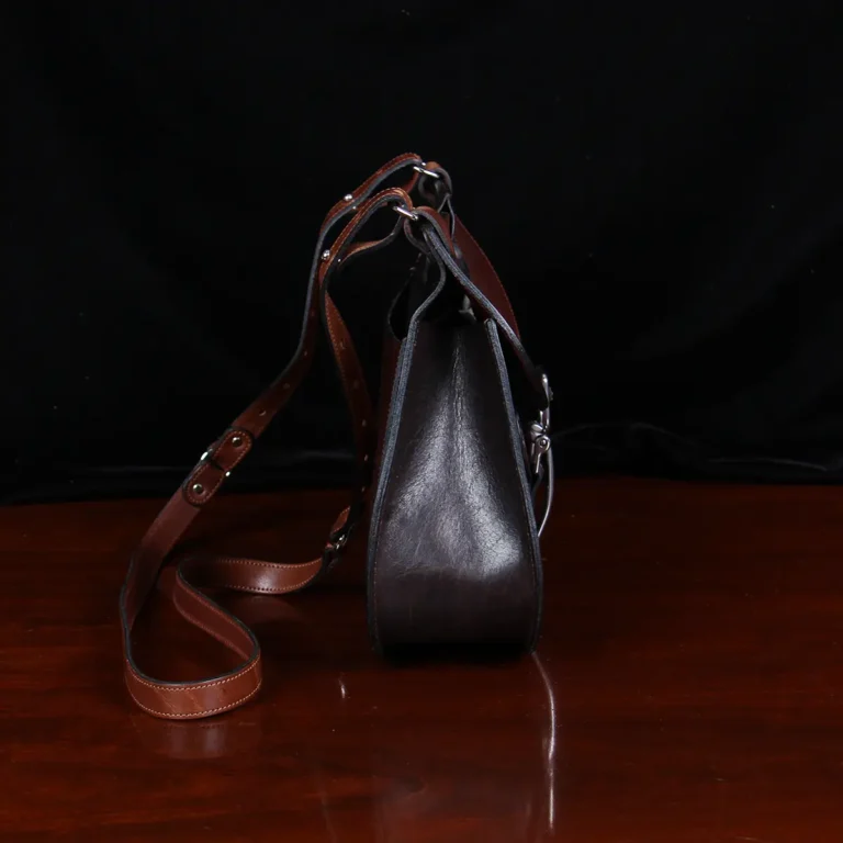 no 18 leather huntbag in tobacco buffalo - side view with iphone - on a wood table with dark background
