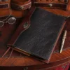 Dark drown buffalo leather composition journal cover on small antique desk with spectacles and antique pen beside it