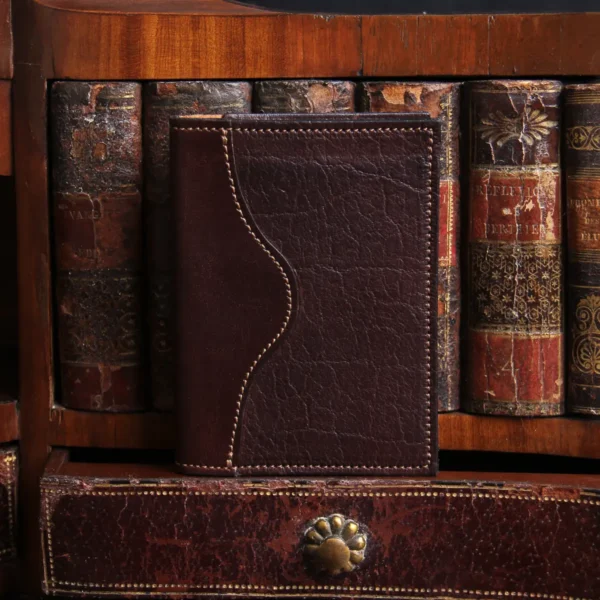 American buffalo tobacco brown no7 card wallet in front of vintage books with CL Buffalo logo in bottom right hand corner
