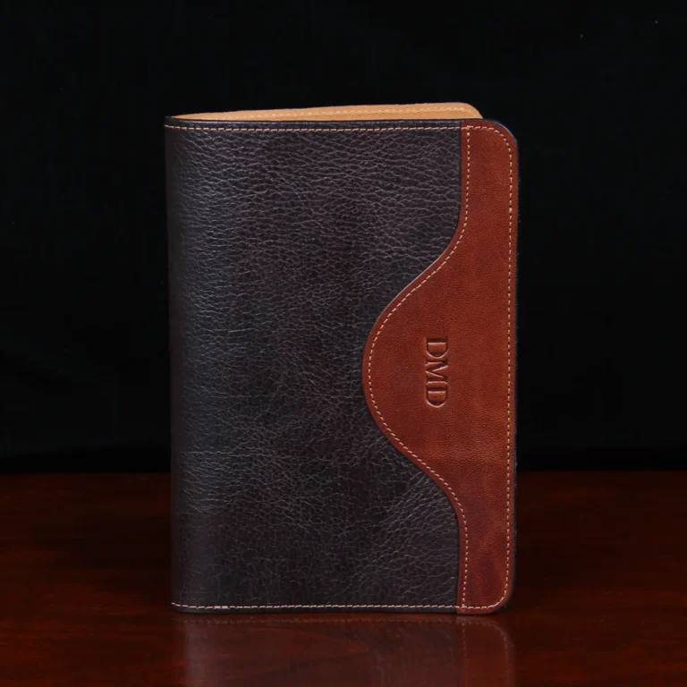 Leather travel portfolio in tabacco brown american buffalo on a wood table - front view