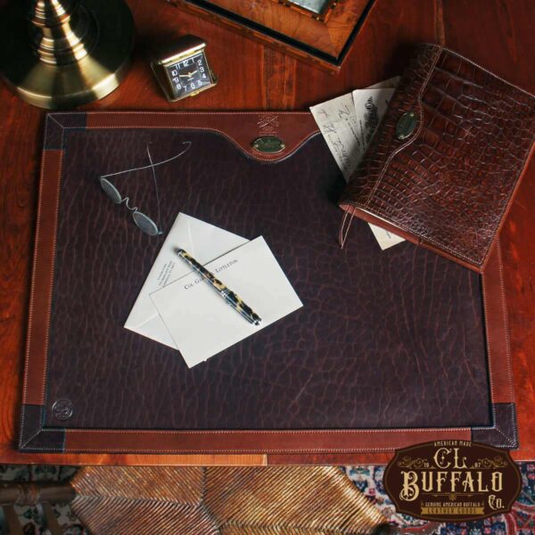 American Buffalo Desk Pad with variety of papers and writing utensils on a table top
