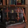 No. 1943 Navigator Briefcase in Tobacco Brown American Buffalo with Vintage Brown Steerhide trim - front view in an antique chair in front of a bookcase