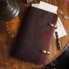 no 28 legal size leather portfolio in tobacco buffalo on a wood table with a pen, glasses, and paper