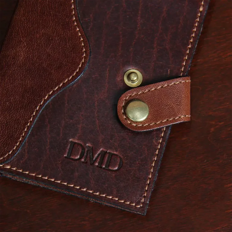 dark brown leather wallet laying on table showing the snap unsnapped