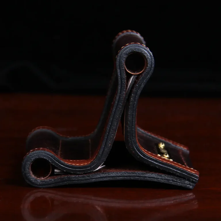 side view of dark leather business card holder sitting on wood table