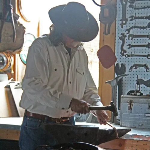 Colonel in his workshop shaping a piece of hardware with a hammer