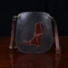 CL - dark brown leather Bella Bag small crossbody with boot on front made from alligator hide sitting on a wood table and black background - id 001