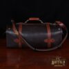 dark brown buffalo leather duffel bag on table - back view with shoulder strap