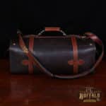 dark brown buffalo leather duffel bag on table - back view with shoulder strap