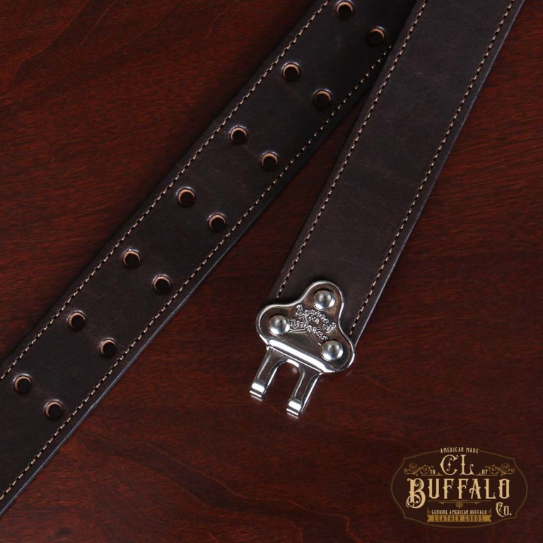 close-up view dark brown leather belt with nickel hardware on wood table